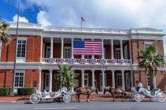 Two horse-drawn carriages parked in front of the historic 1861 United States Customs House in Galveston
